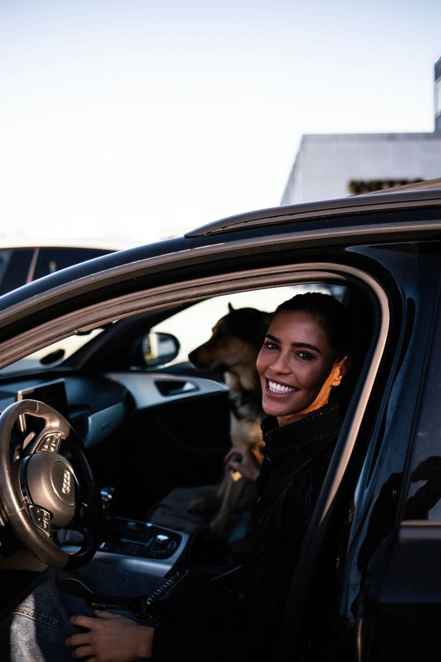 A smiling woman with her dog inside a car in Copenhagen, Denmark.